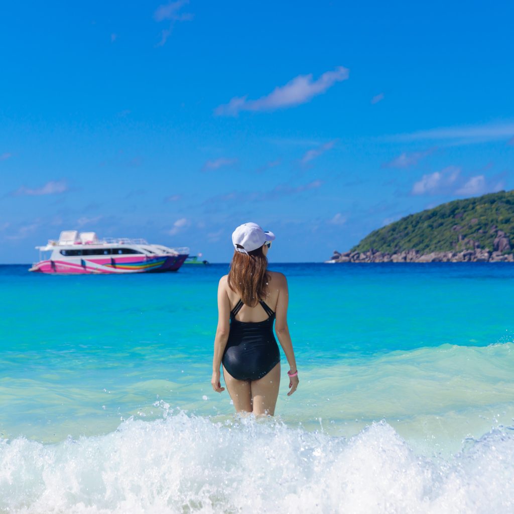 Traveler entering clear turquoise sea at a Similan Islands beach