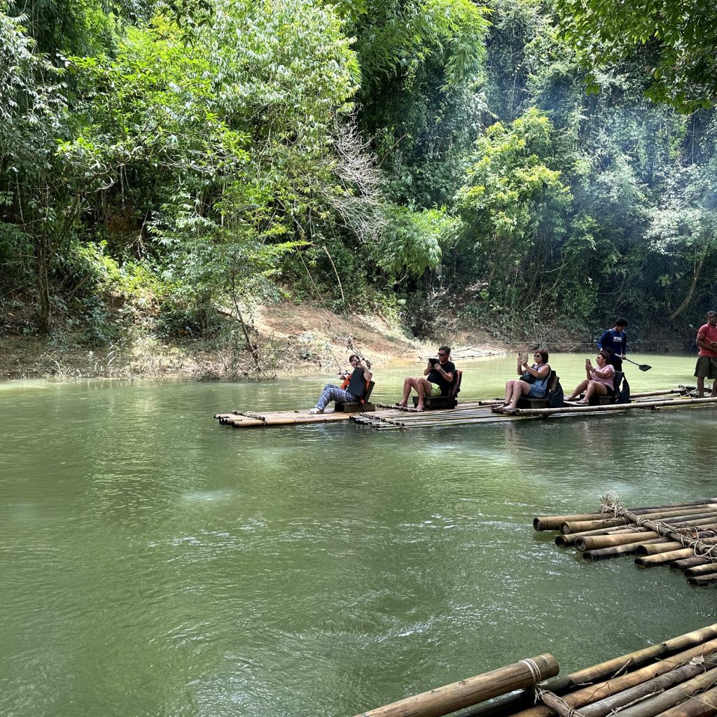 Bamboo rafts with guests and a local raft guide on the green Sok River surrounded by jungle in Khao Sok