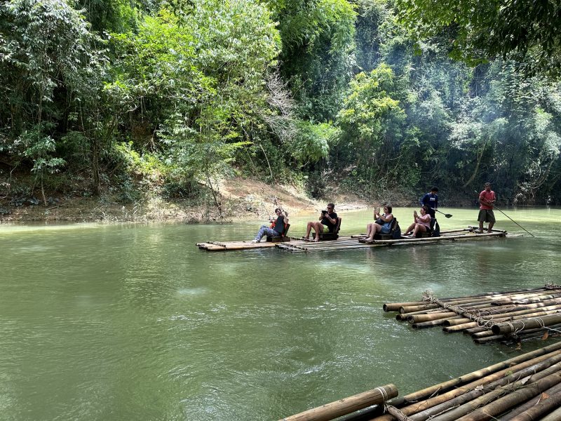 Bamboo rafts with guests and a local raft guide on the green Sok River surrounded by jungle in Khao Sok